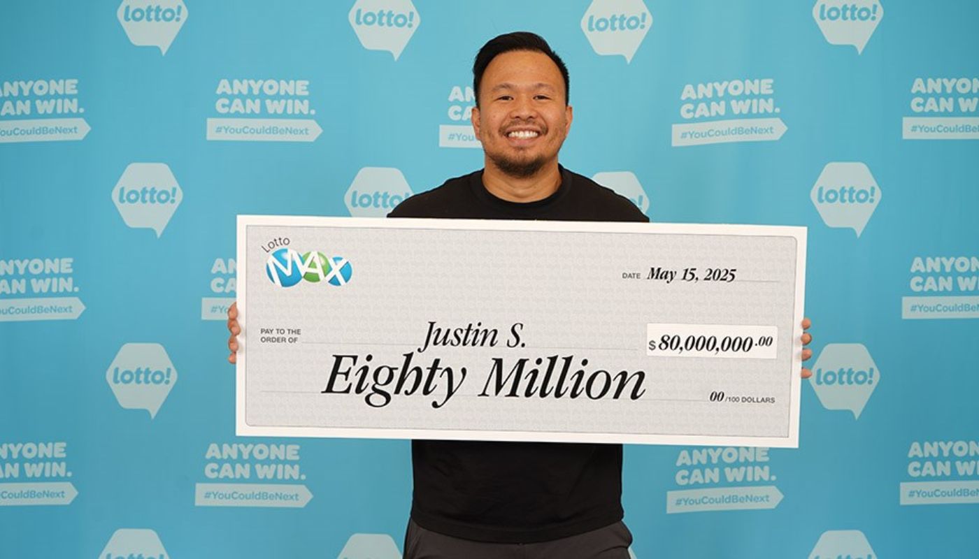 Justin Simporios with his $80 million Lotto Max check.