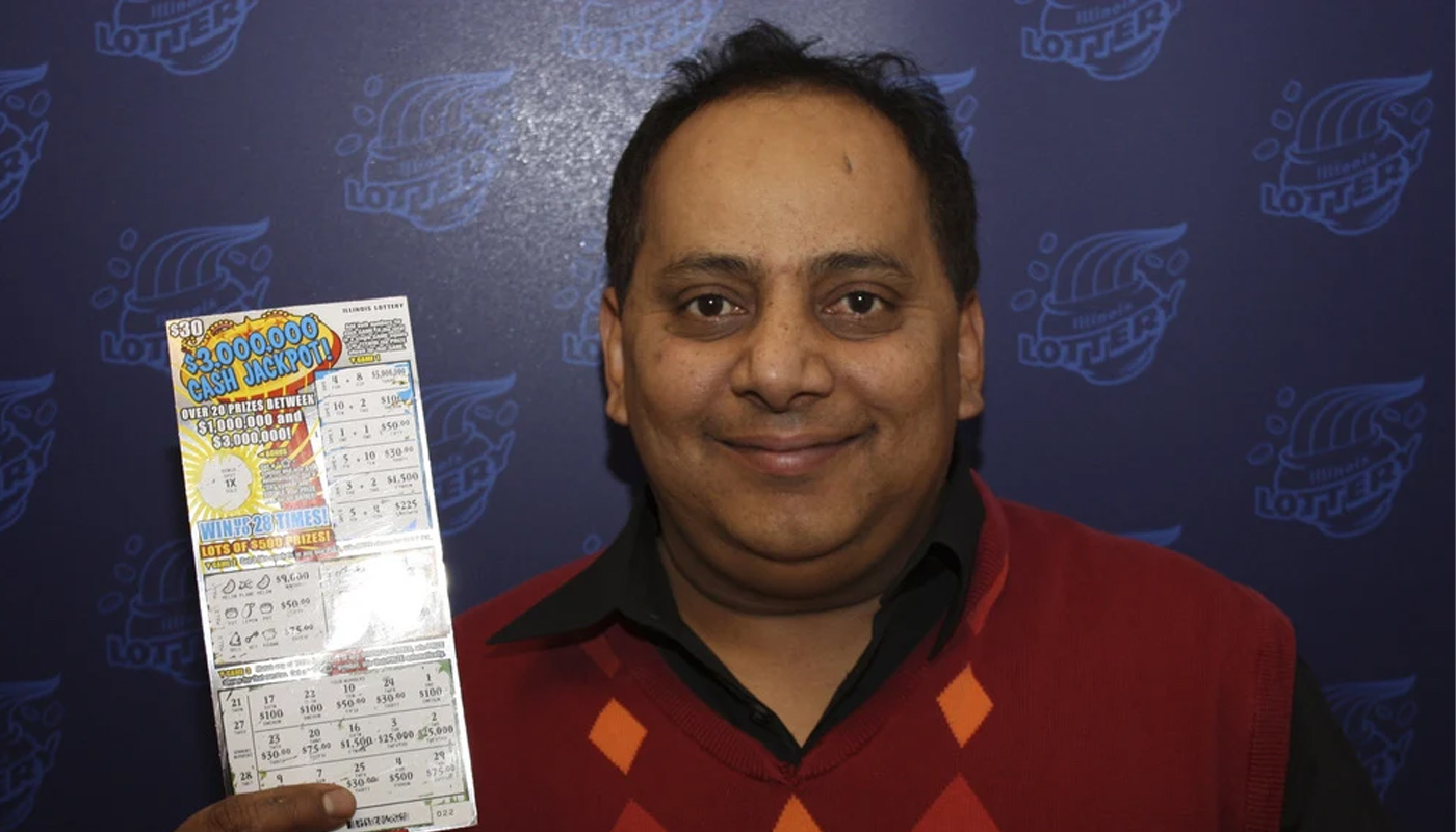 Urooj Khan holding his winning scratch-off ticket from the Illinois Lottery.