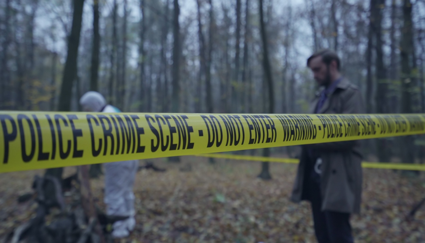 A detective and forensic team member on a crime scene in the woods.