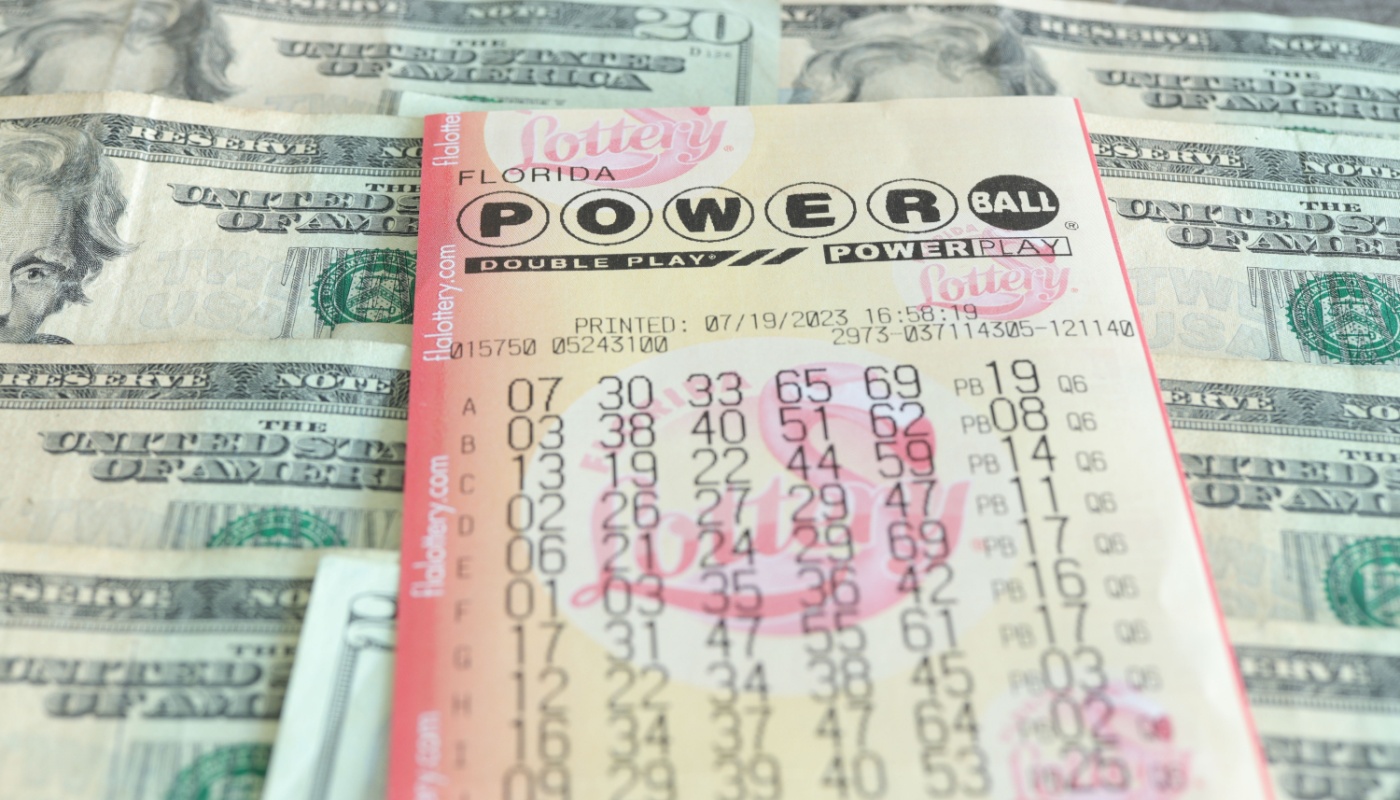 A Powerball ticket over dollar bills.
