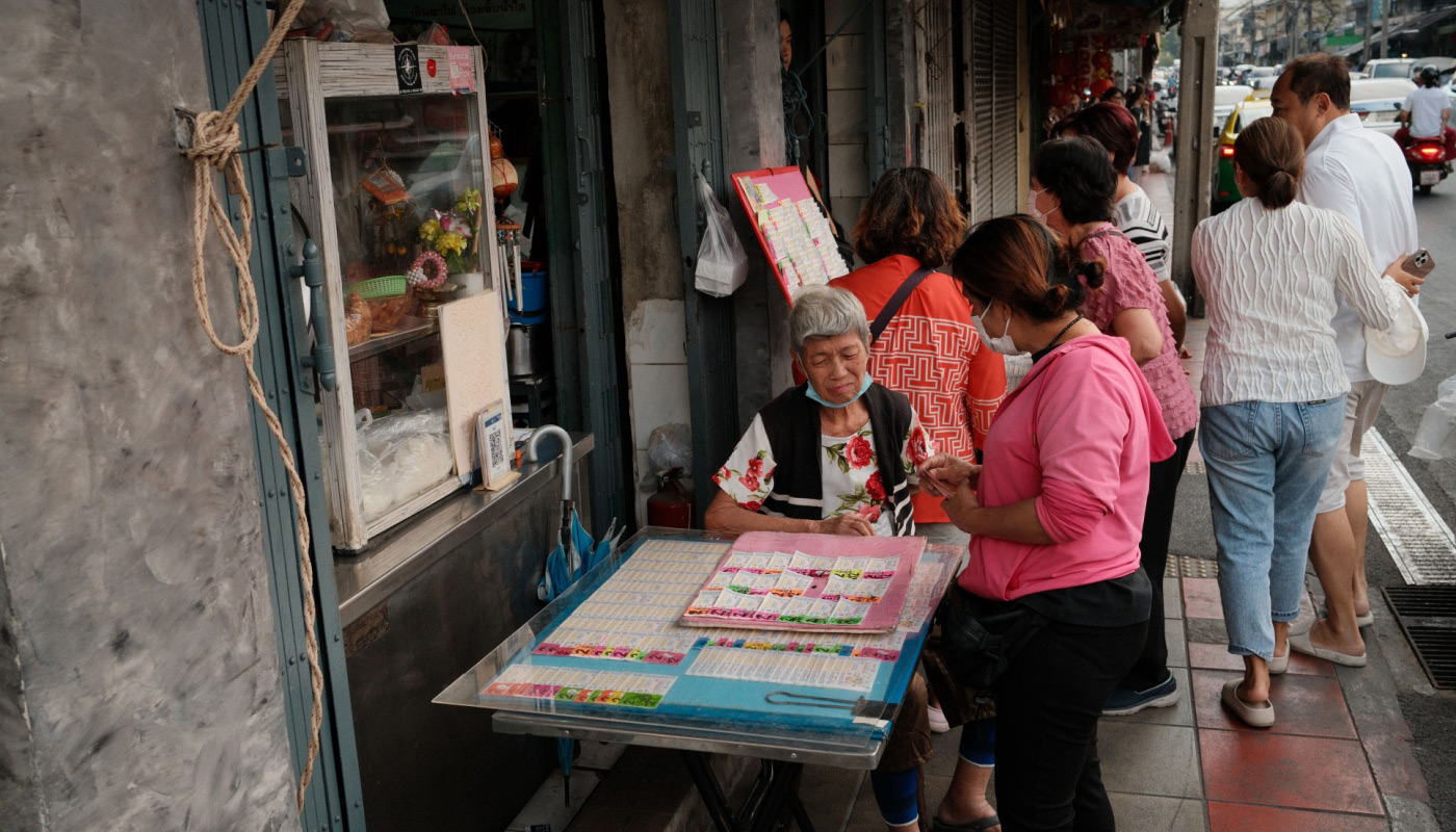 An elderly street vendor can be seen selling lottery tickets in the streets of Bangkok, Thailand.
