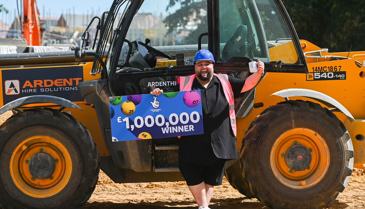 Adam Lopez, 39, of Mattishall, UK, holding his check in front of a forklift.