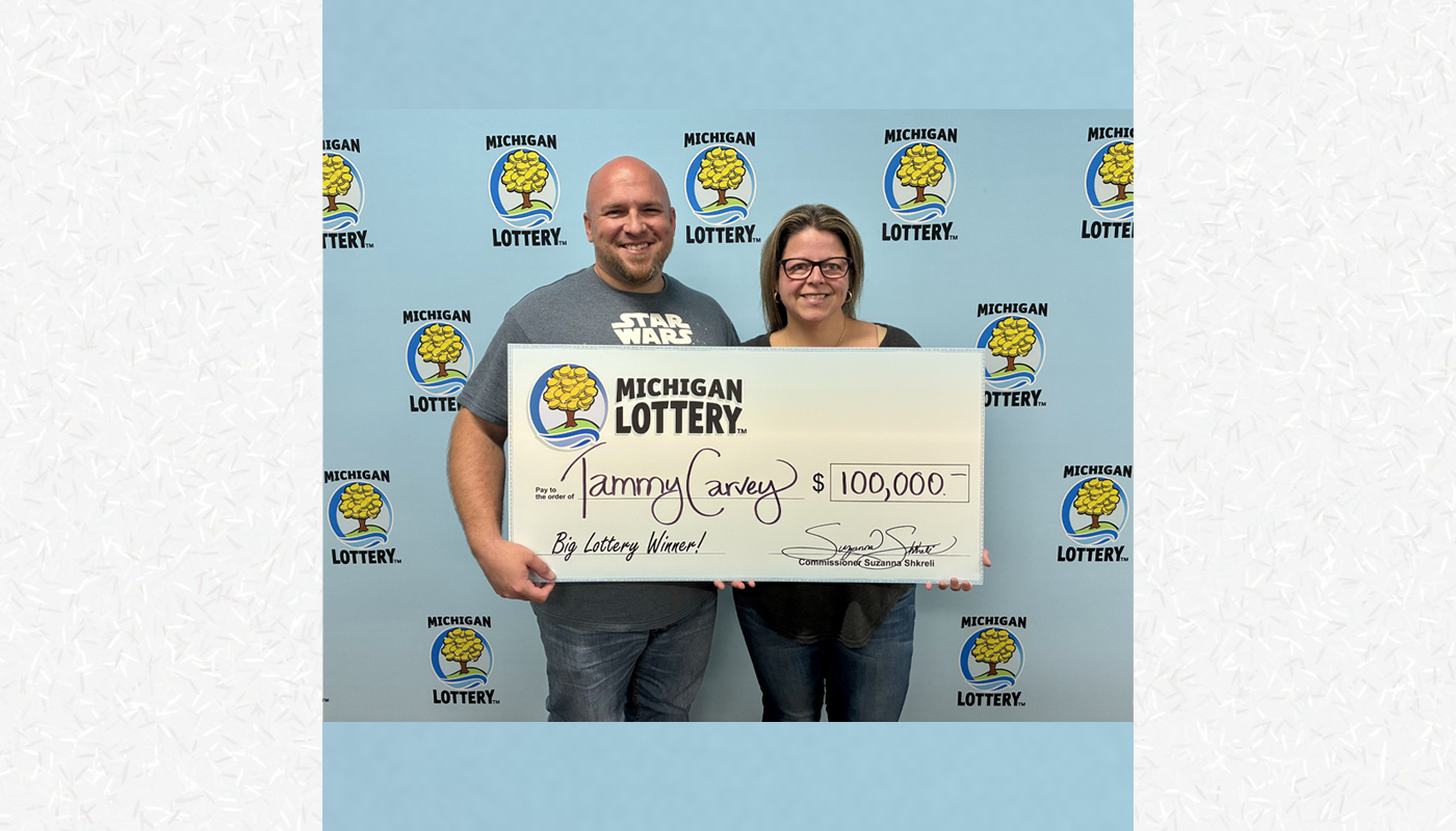 Powerball winner Tammy Carvey holding her $100,000 Michigan Lottery check.