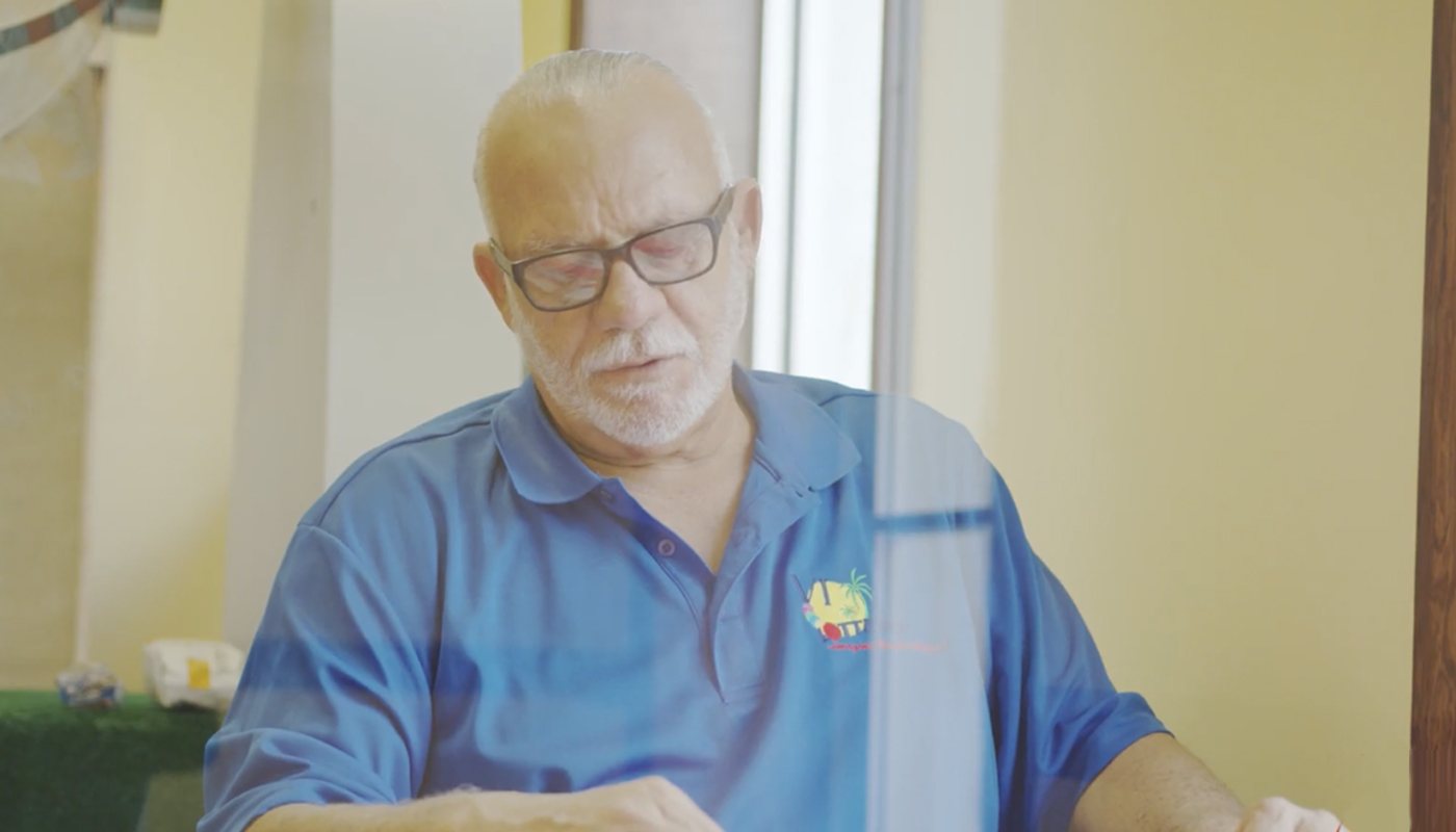 A elderly man with a shirt with the U.S. Virgin Islands Lottery logo.
