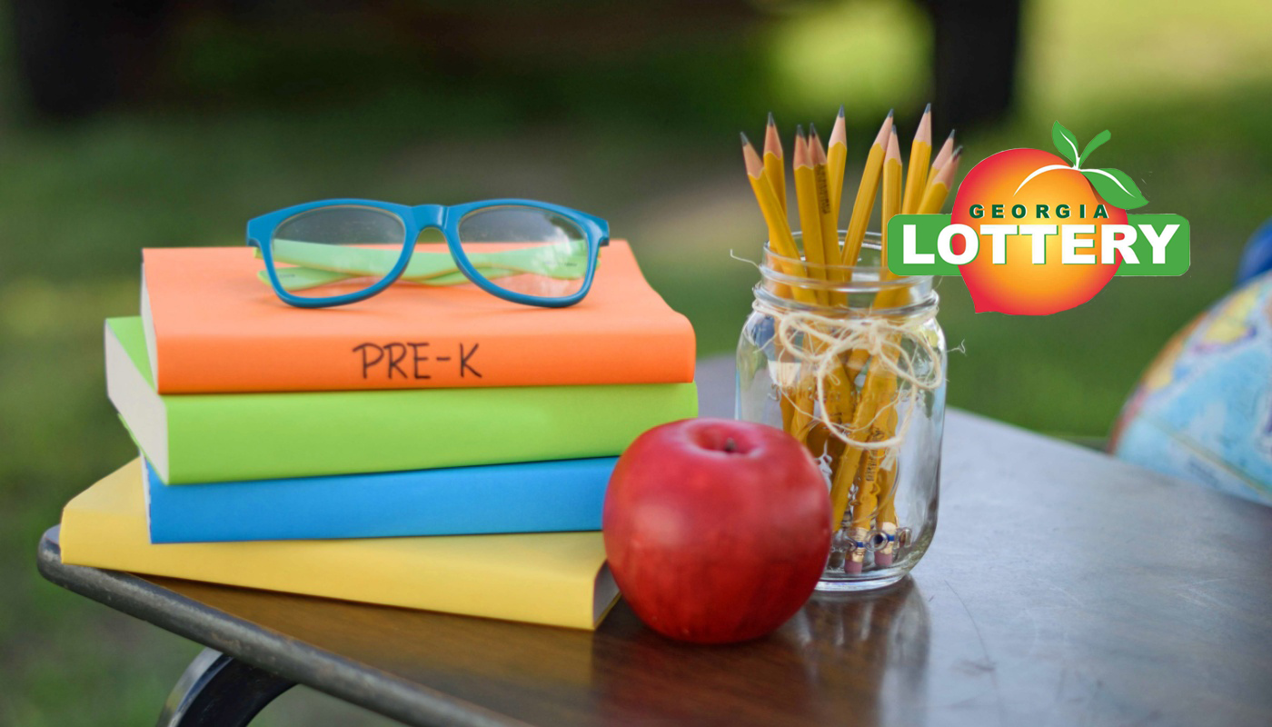 A table with Pre-K supplies, an apple, and the Georgia Lottery logo.