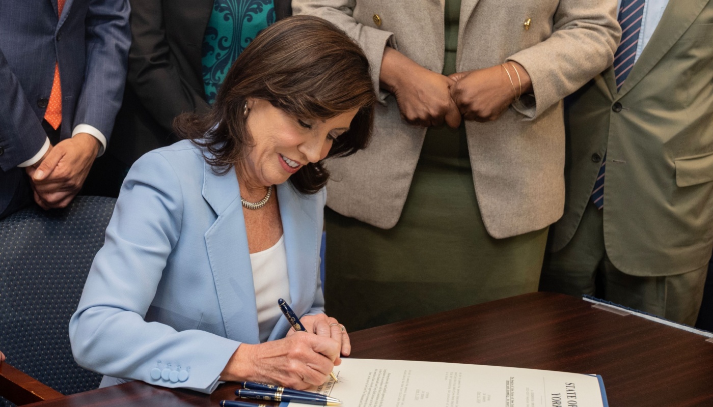 New York Gov. Kathy Hochul signing a bill on a desk.