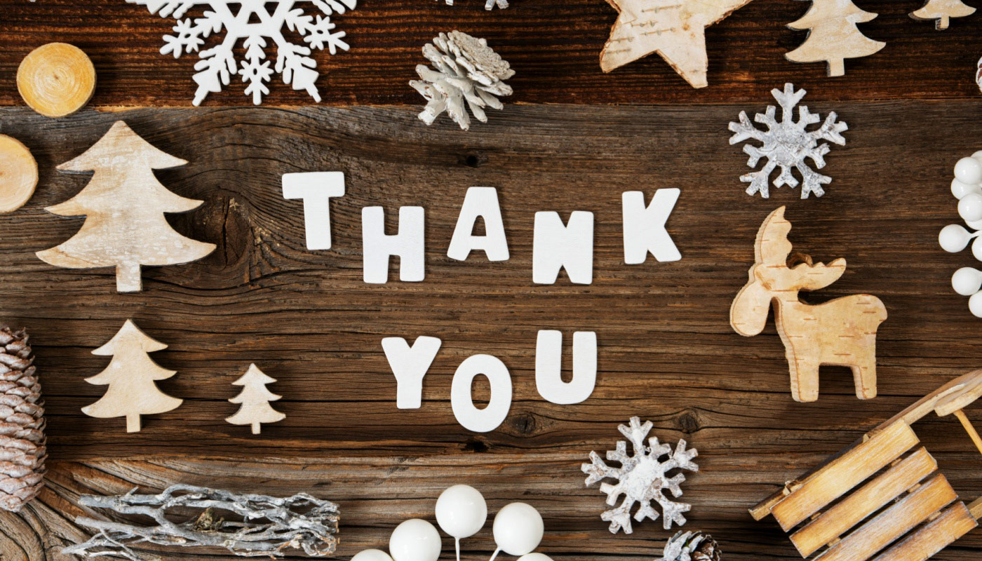 Letters on a table spelling "Thank you" with Christmas ornaments surrounding it.
