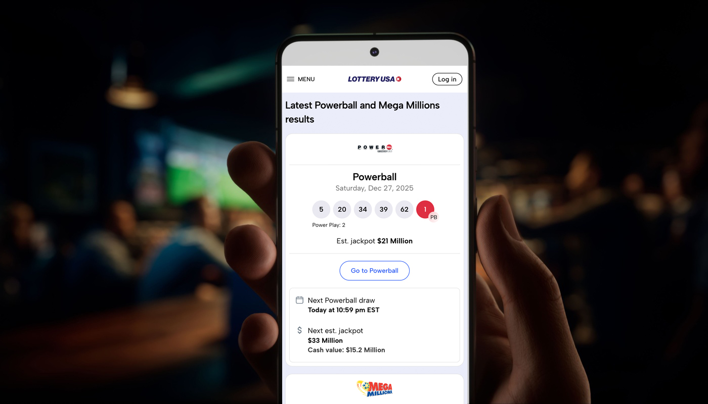 A hand holding a mobile device displaying the Lottery USA website.