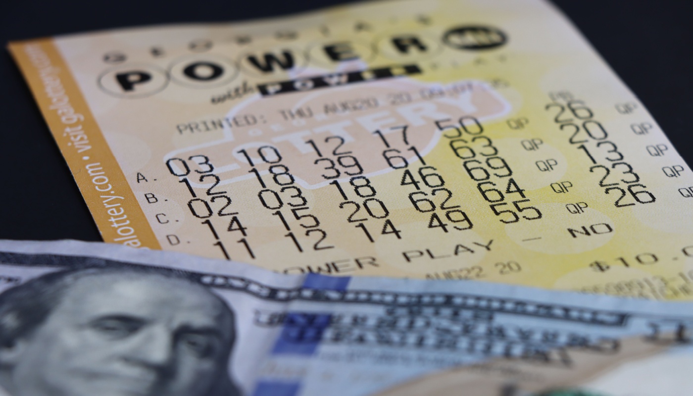 A Powerball ticket and a dollar bill on a table.