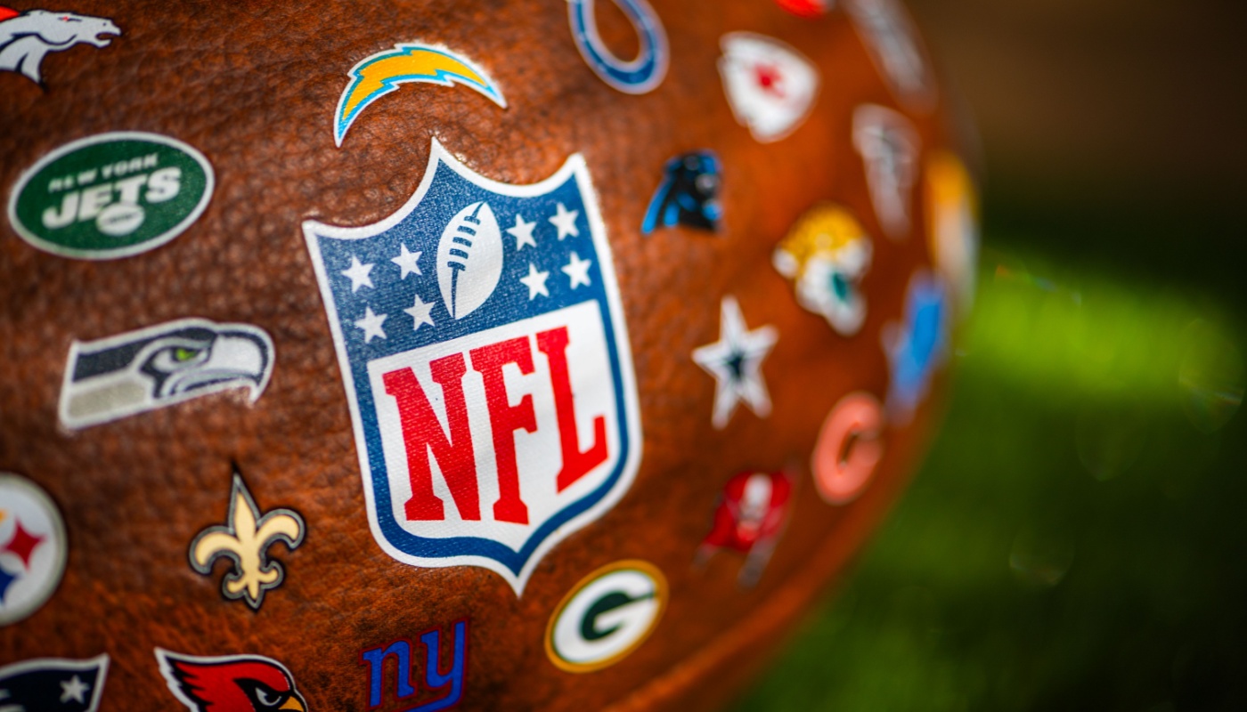A football with the logos of the NFL and it's participating teams.