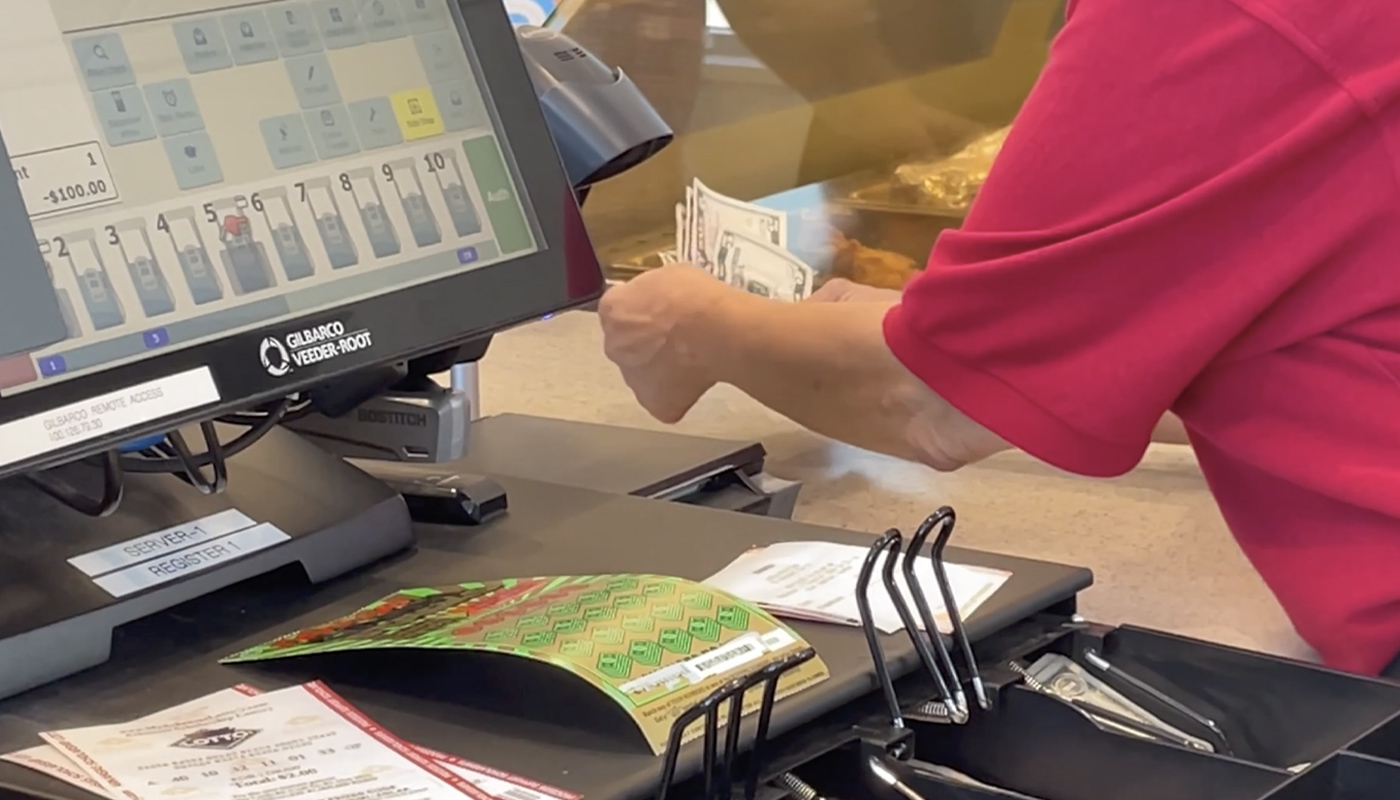 An Arkansas Lottery retailer paying out a lottery prize to a customer.